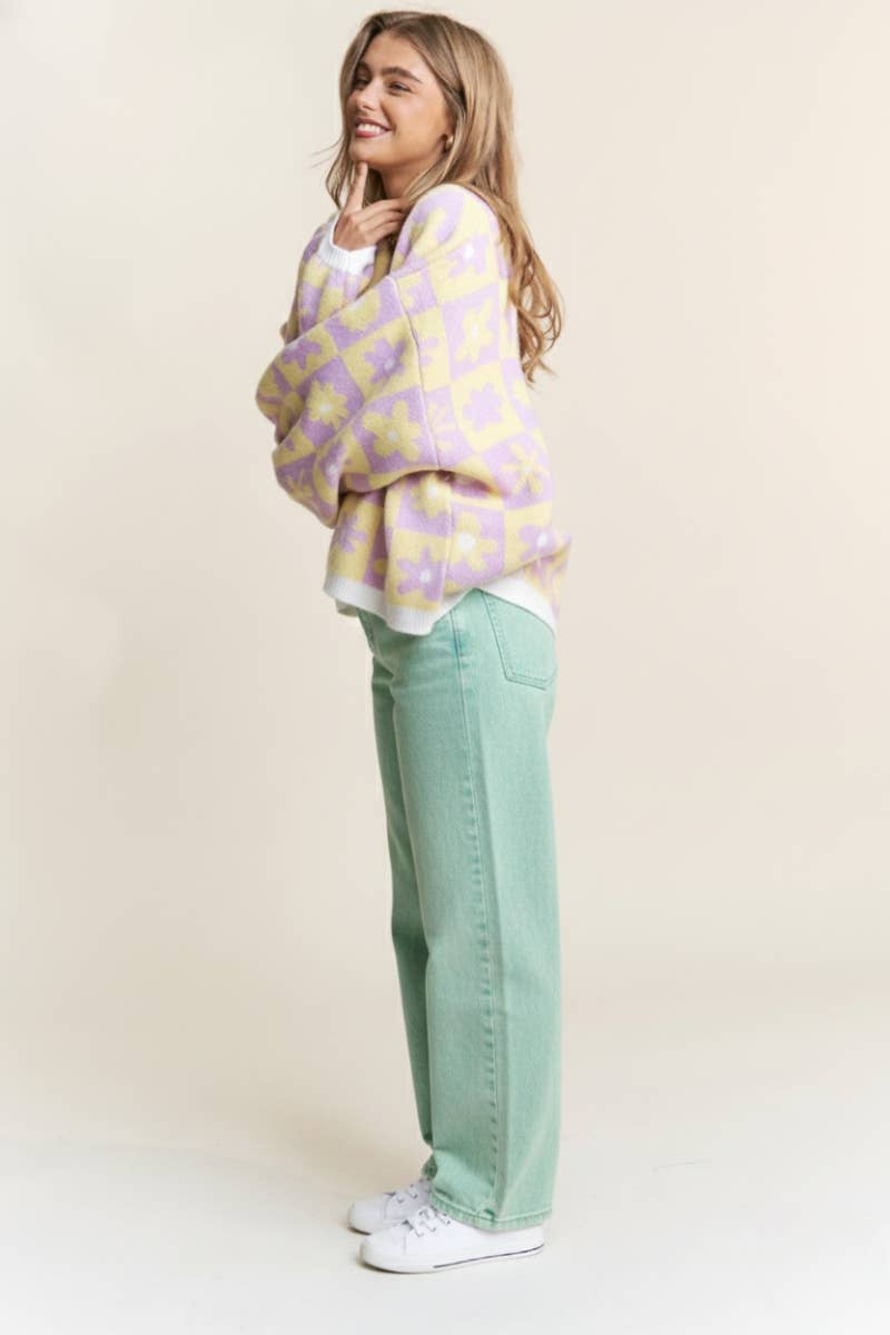 Woman wearing a purple and yellow floral-patterned sweater against a beige background
