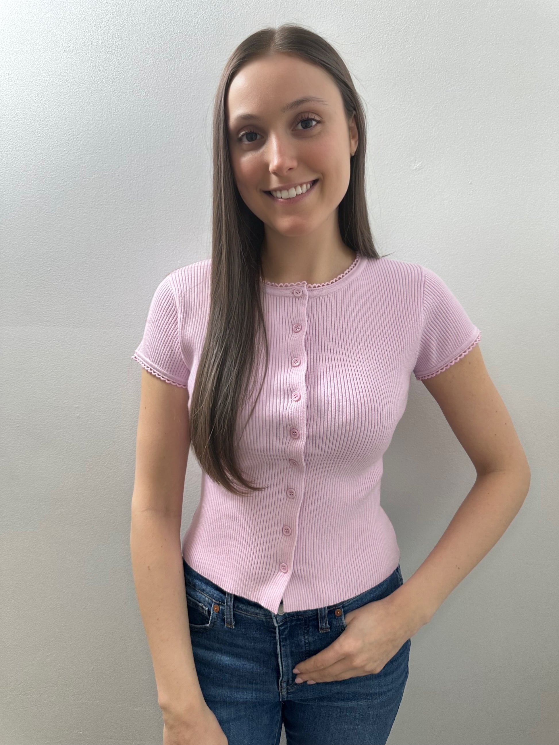 Woman wearing a pink ribbed knit shirt against a plain background