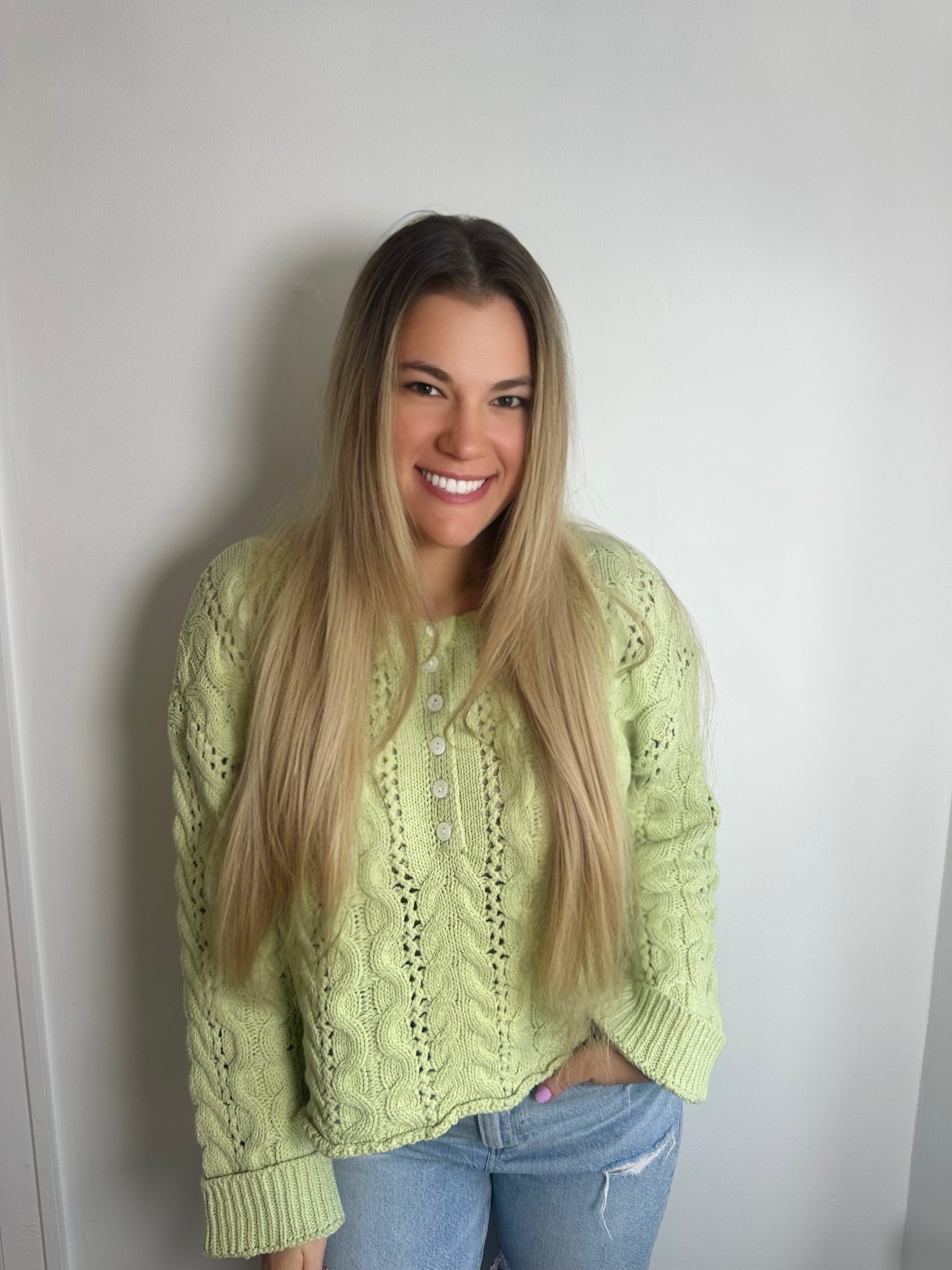 Woman wearing a light green sweater against a plain background