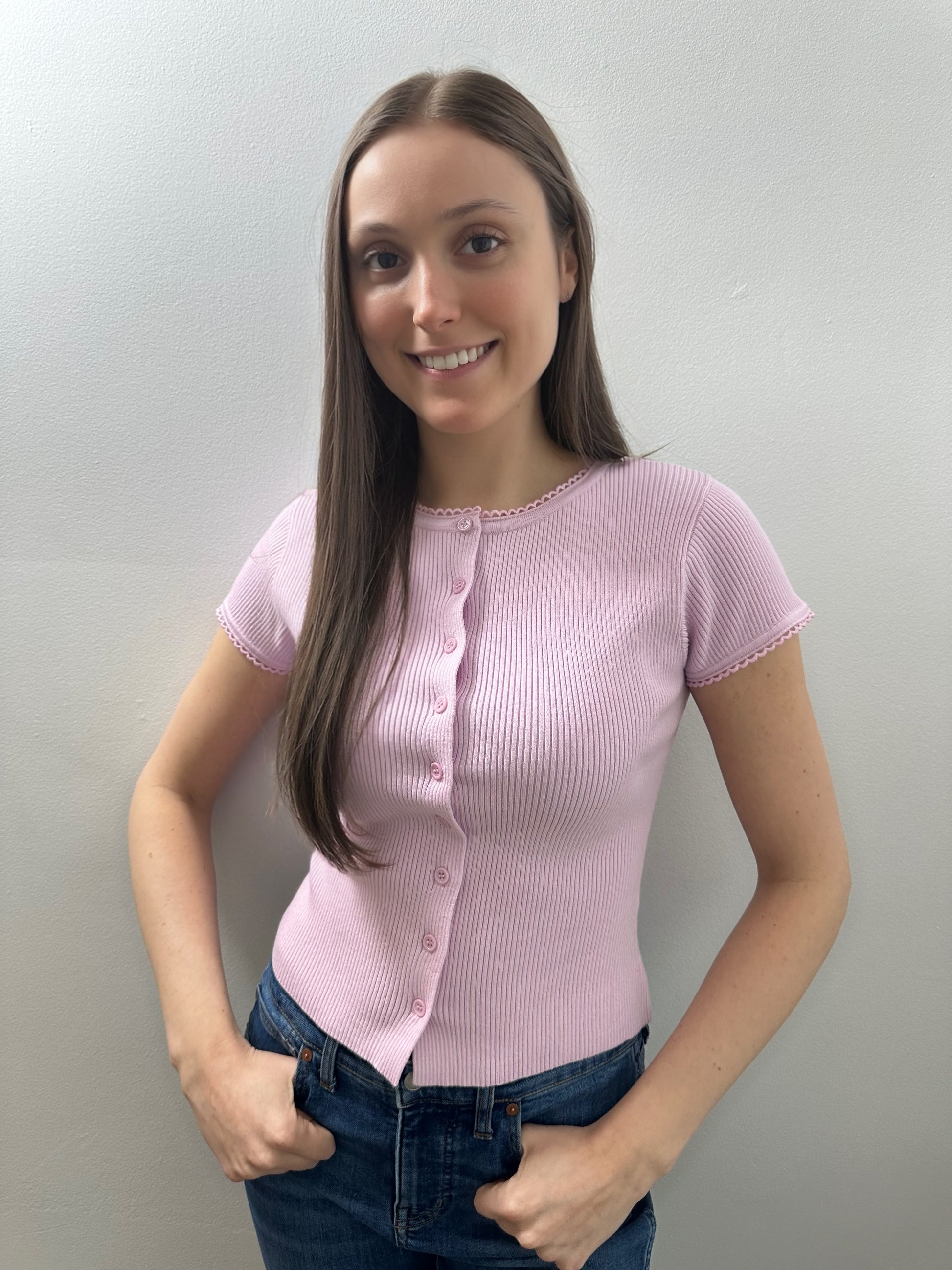 Woman wearing a pink short-sleeve shirt against a plain background