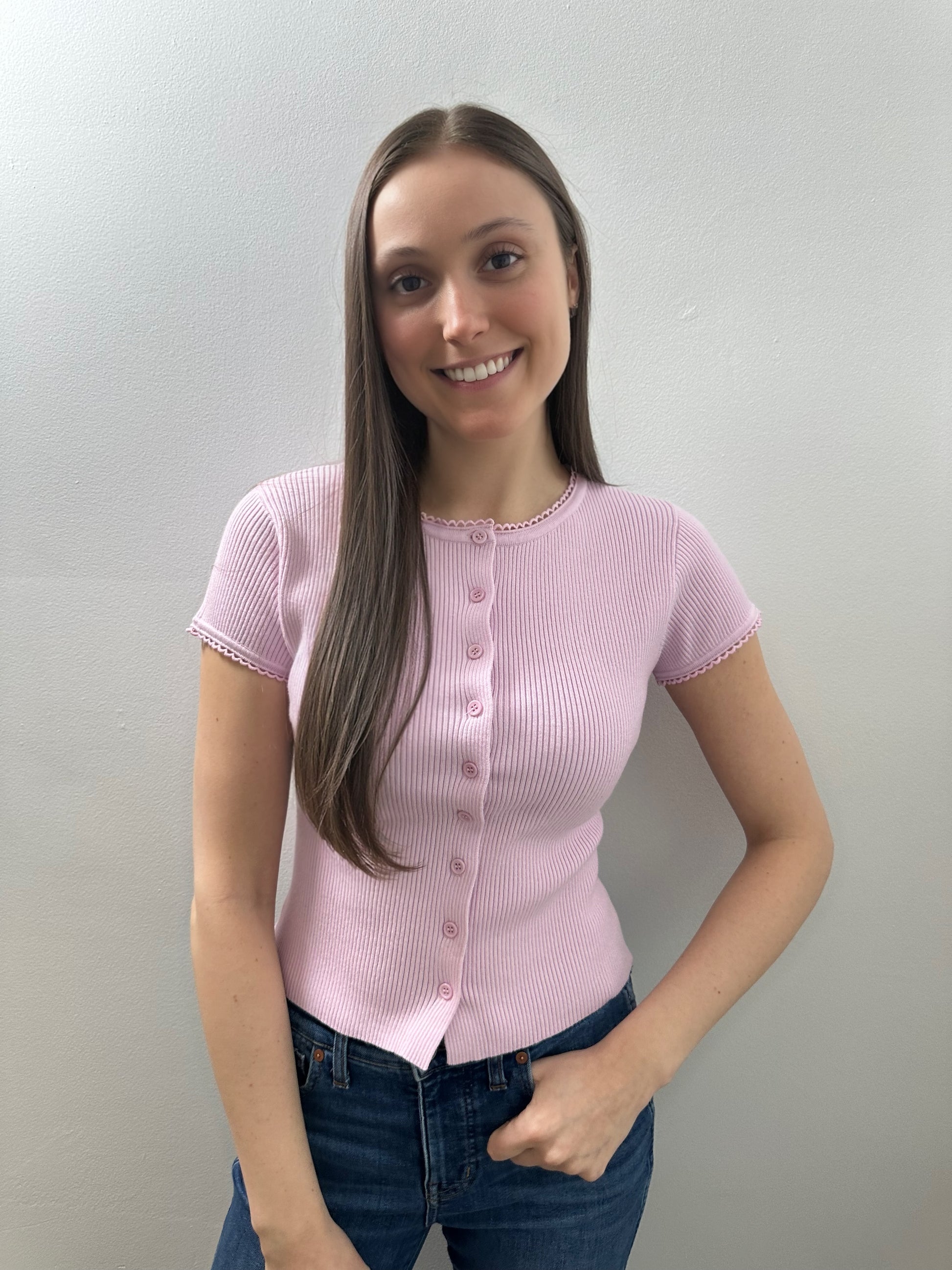 Woman wearing a pink short-sleeve blouse against a plain background