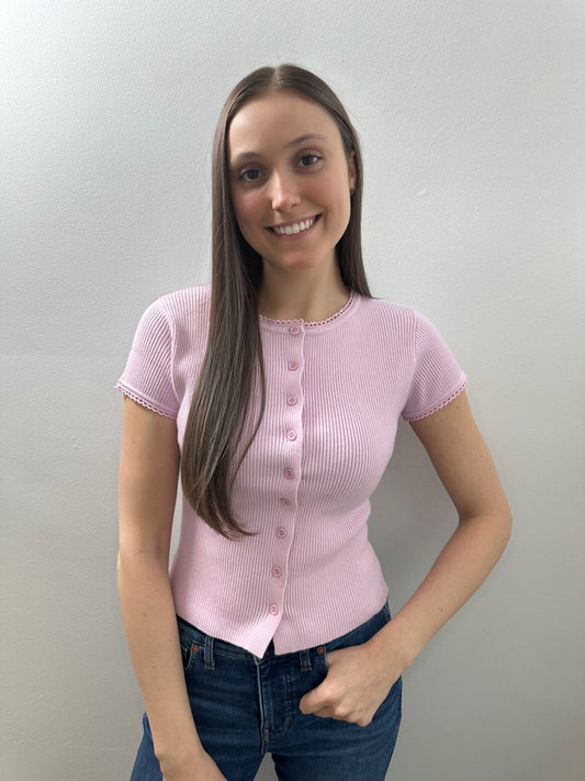 Woman wearing a pink short-sleeve blouse against a plain background