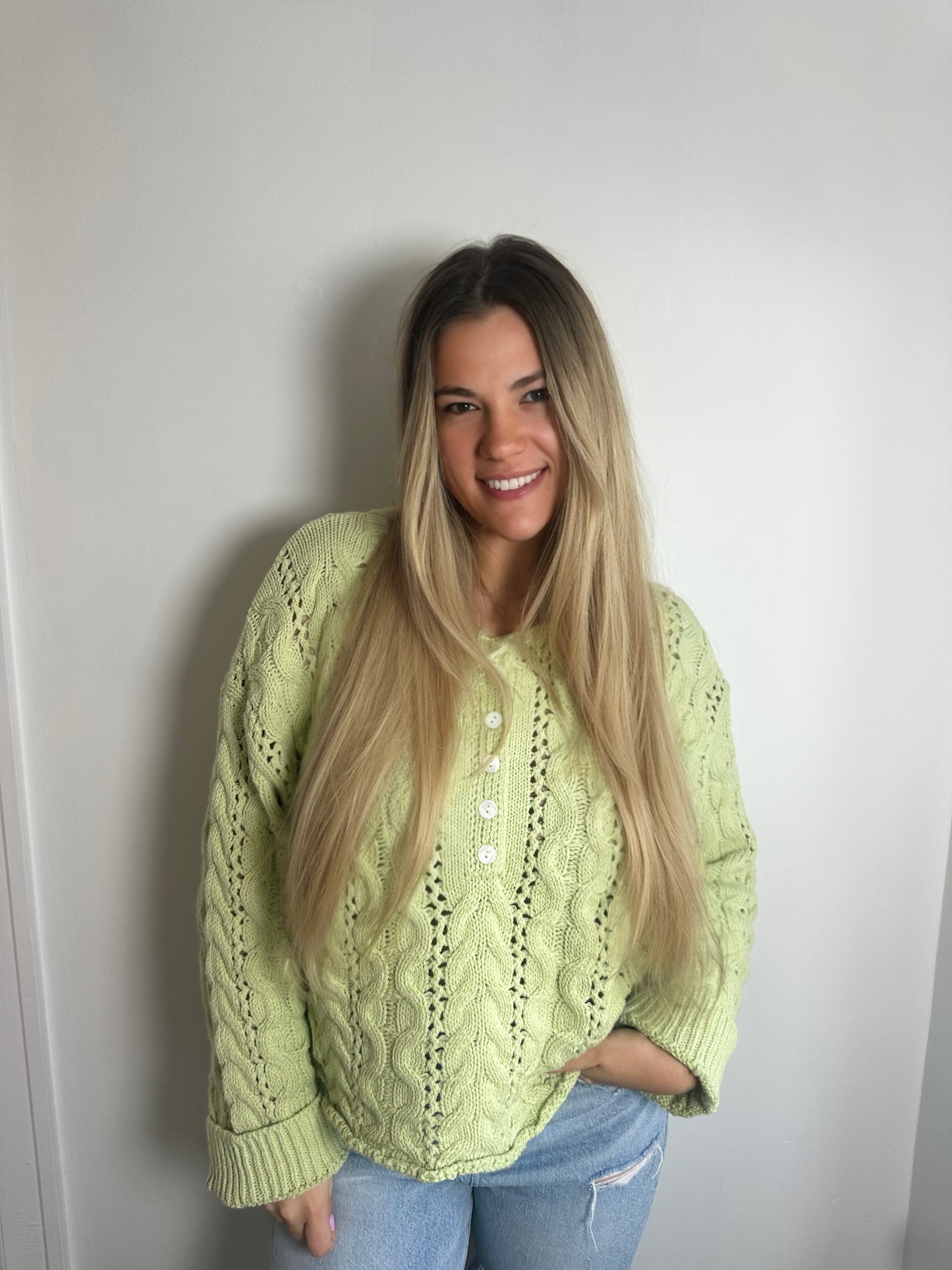 Woman wearing a light green sweater against a plain background