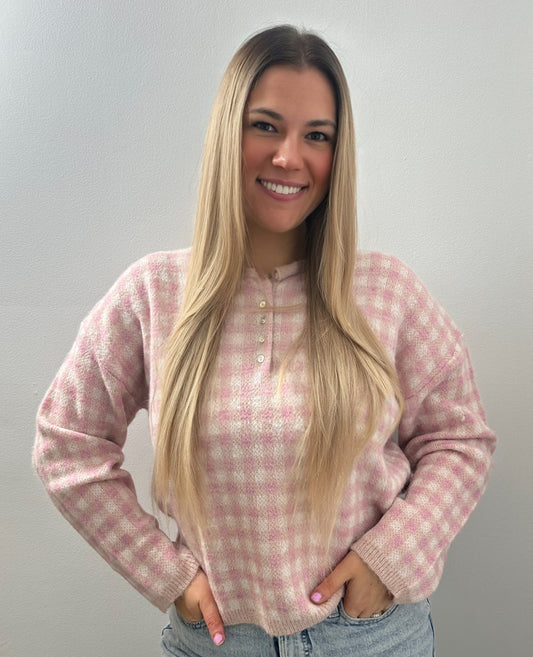 Woman wearing a pink checkered sweater against a plain background