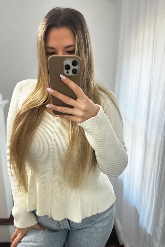 Women taking a mirror selfie wearing a white long sleeve top