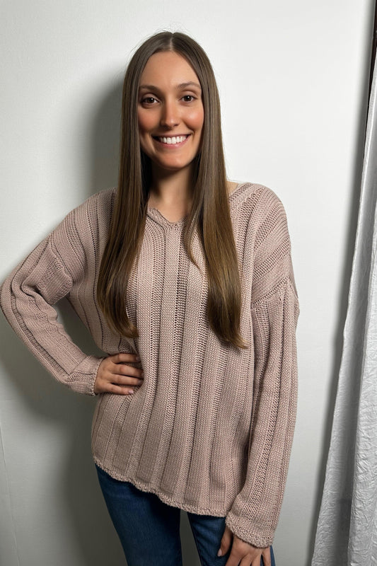 Woman wearing a beige sweater against a white wall
