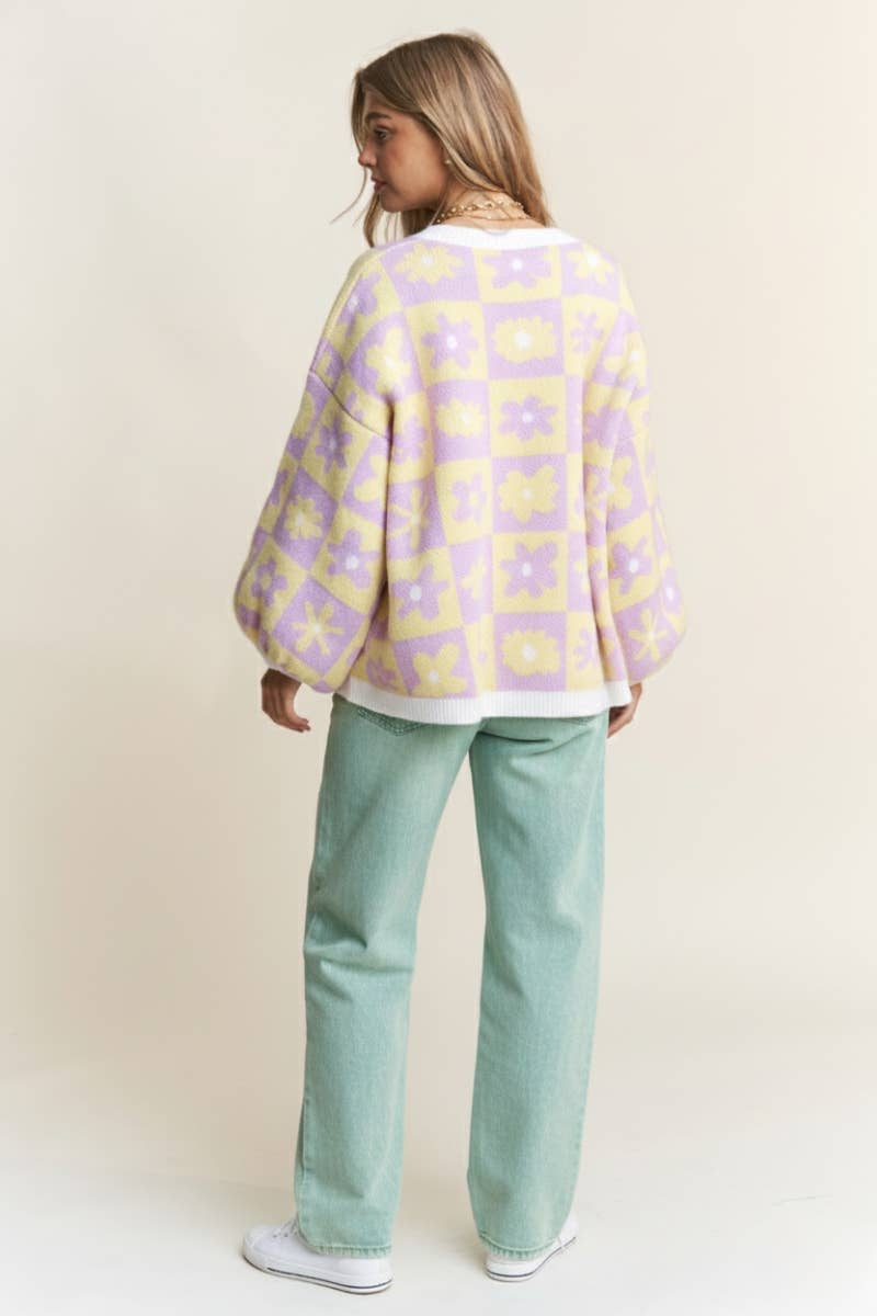 Woman wearing a purple and yellow floral-patterned sweater against a beige background
