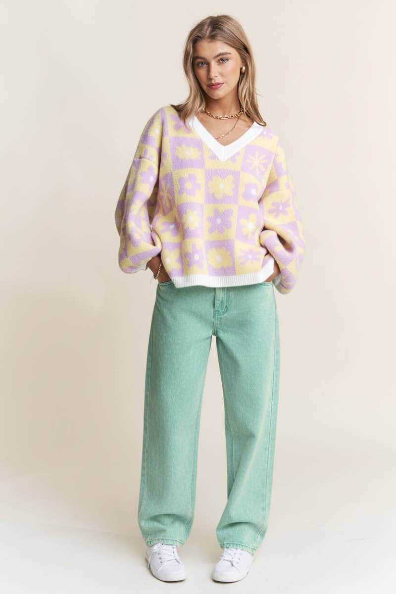 Woman wearing a purple and yellow floral-patterned sweater against a beige background